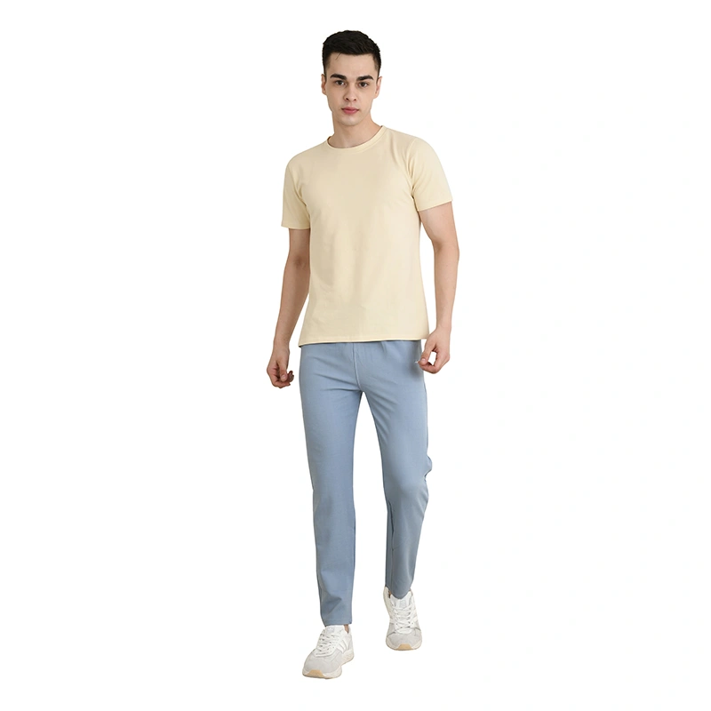 Male model in cream round-neck t-shirt with light blue track pants and white sneakers - menswear ecommerce photography by Lohar Studio Delhi